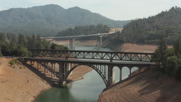 Aerial view of Shasta Lake rising shot of train tracks and bridges in Northern California low water