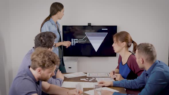 Young Woman Is Presenting Report for Her Colleagues at Business Meeting in Office Room, Showing Data