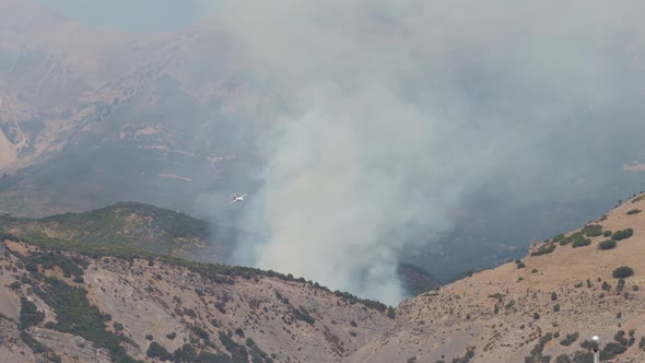 Airplane making test pass in front of wildfire burning on mountainside