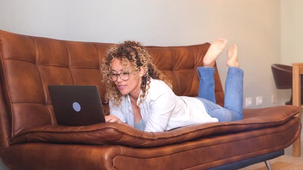 Adult pretty female people watch internet computer contents lay down and relaxing on couch at home