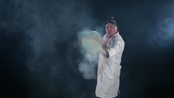 Man Chemist in Uniform Making Interesting Trick with Air Smoke Bubble, Rounds on Black Background