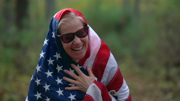 Closeup of pretty, blonde woman with an American flag around her and giving the camera a hip hop mot