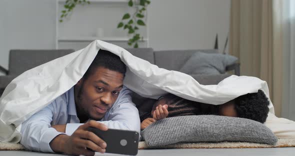 Family Portrait of African American Parents with Little Daughter Asleep Lie Under White Blanket at