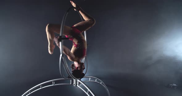 Young Pretty Woman is Doing a Headstand in a Spinning Hoop Gymnastics Show