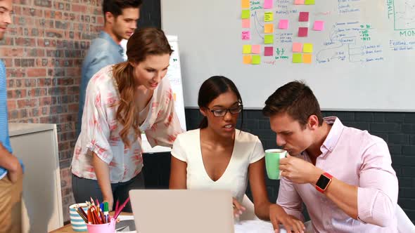 Businesspeople interacting while using laptop