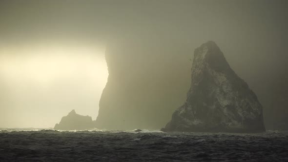 Mist Over the Sea with Rocky Volcanic Cliff is Lit By the Warm Sunset