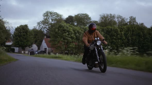 A Motorcycle Driven on a Smooth Road With the Backdrop of a Lush Green Field