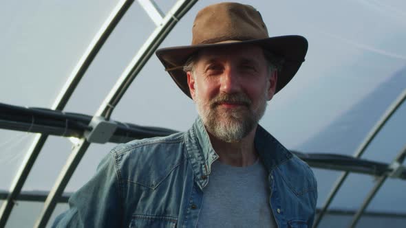 Positive Mature Farmer in Greenhouse