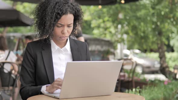 Thinking Happy African Woman Working on Laptop Outdoor Cafe