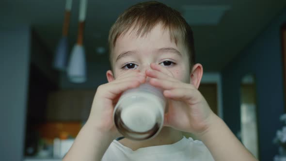 Cute Child in Kitchen Drinks Yogurt Milk and Kefir Licks Her Lips