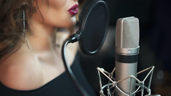 Beautiful sexy young woman singing. Female vocal. Professional recording studio.