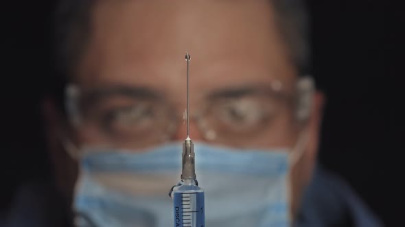Doctor Holds the Syringe in His Hand and Presses the Valve To Release the Air From the Syringe,drops