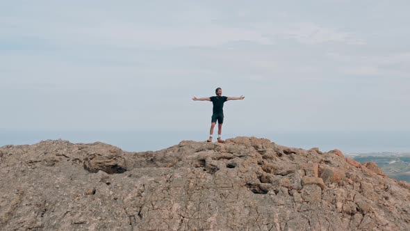 Young climber celebrates the top of the mountain with open arms