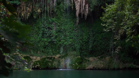 Large Waterfall Drops Fall From Cliff Into Calm Lake Water