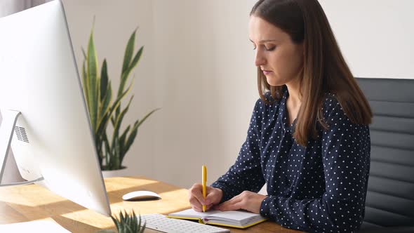 Thoughtful and Concentrated Female Employee Takes Notes