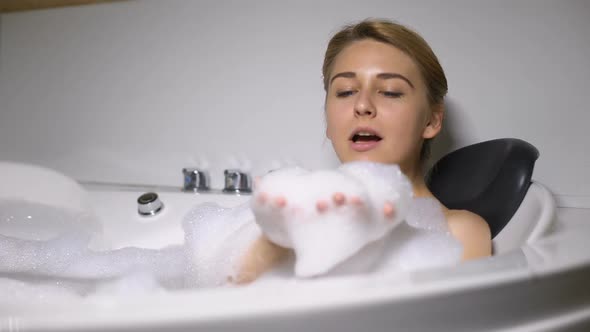 Funny Female Lying in Bath, Blowing Foam Bubbles Into Camera, Childish Mood