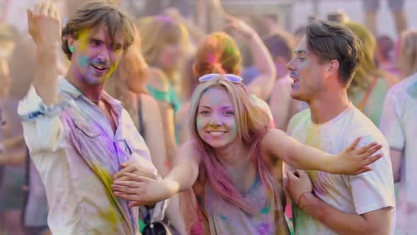 Funny Male and Female Covered in Paint Having Fun and Waving Hands at Holi Fest