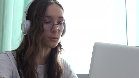 Girl Student Wearing Headphones Studying Online with Internet Teacher Looking at Laptop