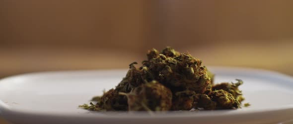 Plate with cannabis buds being moved on a table,close up,shallow depth of field