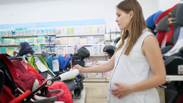 Pregnant Woman Chooses a Stroller in a Baby Store