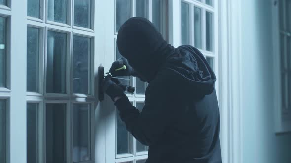 Thief Man Holding Flashlight Trying To Open The Door Of Someone's House