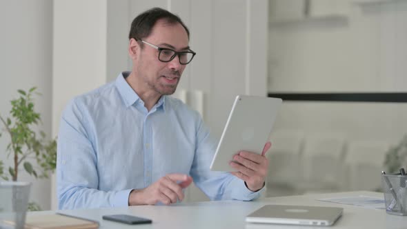 Video Call on Tablet By Middle Aged Man in Office