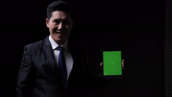 Businessman posing and looking at camera with presentation data tablet green screen