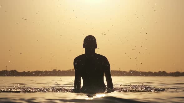 Silhouette of Young Cheerful Woman Splashing River Water at Sunset, Slow Motion