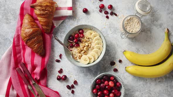 Ceramic Bowl of Oatmeal Porridge with Banana, Fresh Cranberries and Walnuts