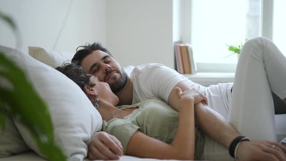 Young Woman and Bearded Man are Kissing While Lying on Bed in Modern Apartment Spbd