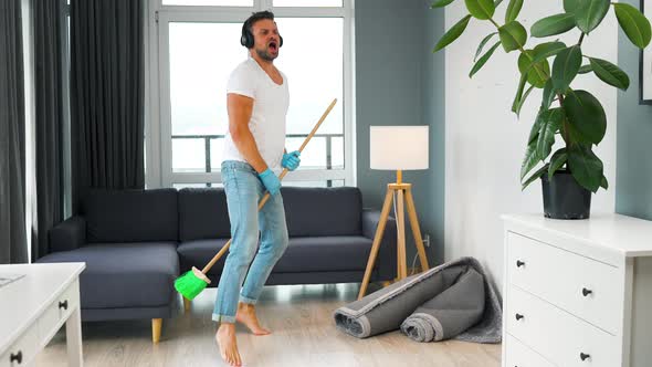 Man in Headphones Cleaning the House and Fooling Around with a Broom