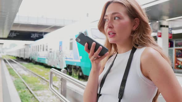 Slow motion young woman outdoor recording vocal message using smartphone