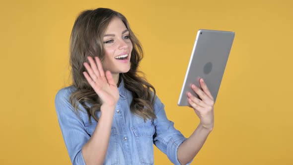 Video Chat By Young Girl Via Tablet Isolated on Yellow Background