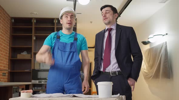 Confident Service Man Explaining Flat Renovation Plan to Young Apartment Owner