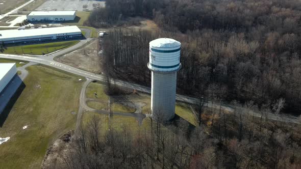 Drone shot of water tower with passing cars, on a spring day.