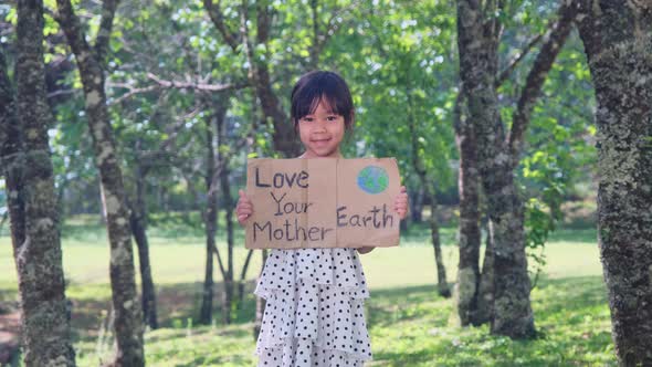 Portrait of a cute Asian preschooler smiling happily in the summer garden. alt