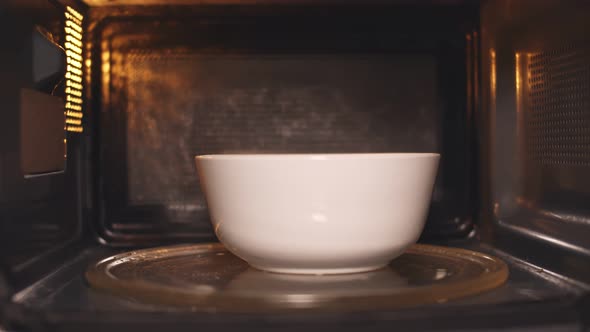 Young Caucasian Man Heating Food in Microwave Oven