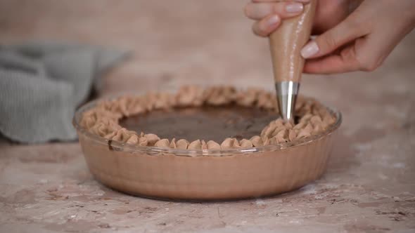 Chef puts chocolate whipped cream inside of a dessert at confectionery.	