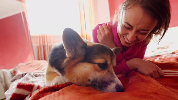 Lovely Young Woman Playing with Funny Dog on Bed