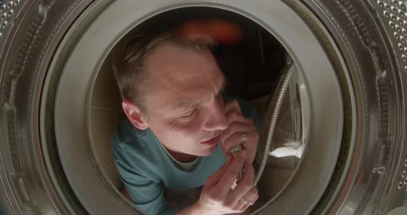 A Man Makes a Shower Head Call From a Washing Machine