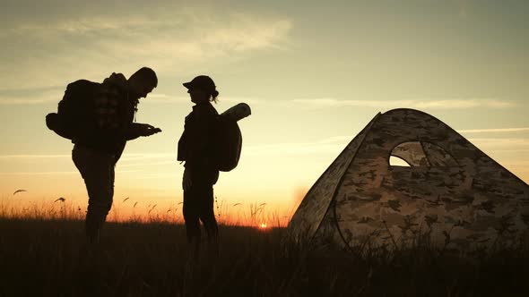 Happy Couple Man and Woman Tourist at Top of Mountain at Sunset Outdoors During a Hike. Silhouettes