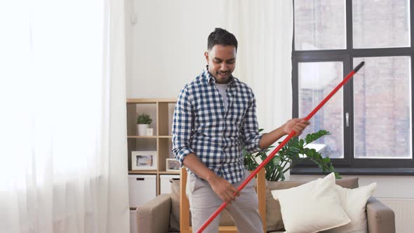 Man with Broom Cleaning and Having Fun at Home 