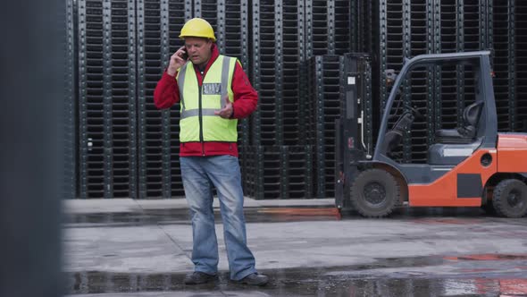 Warehouse worker talking on phone outside factory