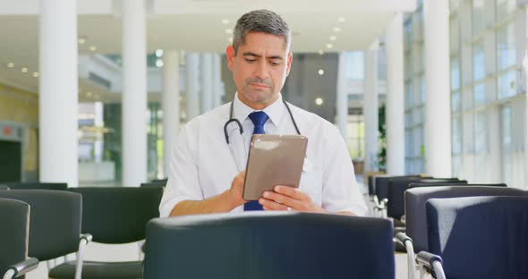 Caucasian male doctor holding digital tablet in the lobby at office 4k