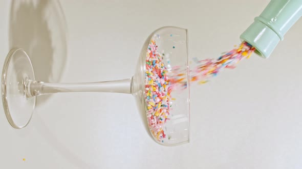 Colorful Candy Confectionery Run Poured Into a Wineglass Glass on Green Background