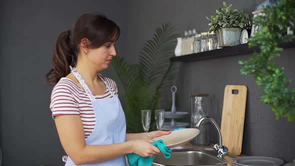 Housewife Wipes the Dishes with a Towel