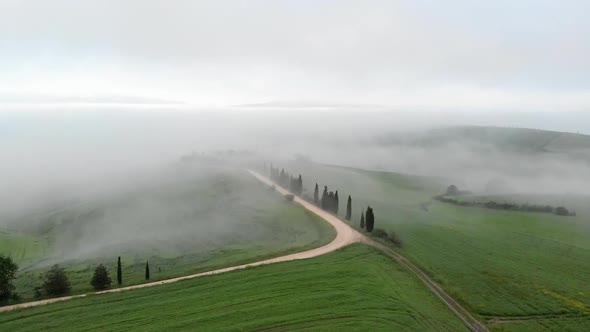 Flying Over the Hills of Tuscany, Italy Covered with Thick Fog Along a Road To a Villa. Aerial Shot