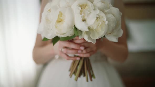 The Morning of the Bride in a White Roses Holds in Her Hands a Wedding Bouquet of Roses. Close Up