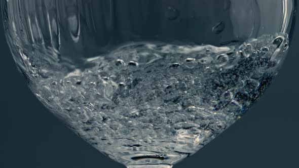 Closeup Water Pouring Glass at Dark Background