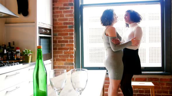 Lesbian couple interacting with each other in the kitchen